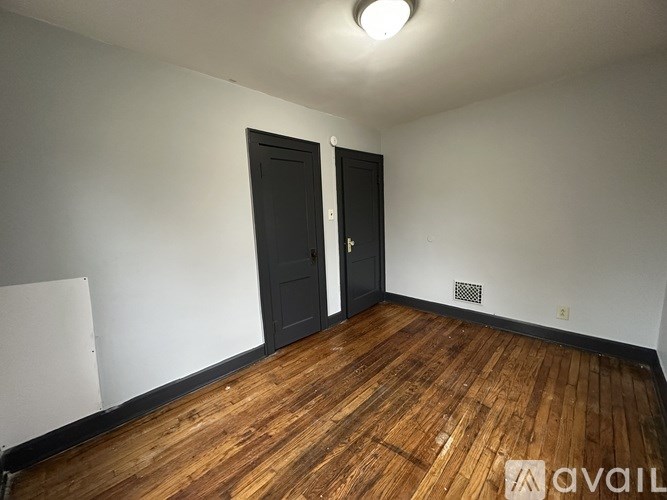 A room with wooden floors and two doors.