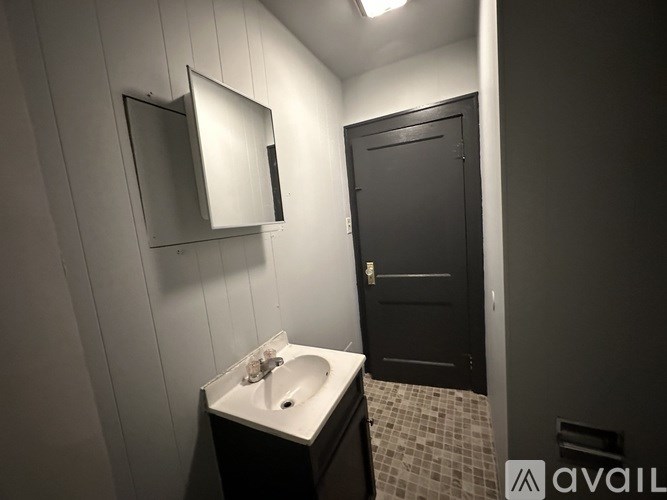 A bathroom with a sink, mirror, and black door.