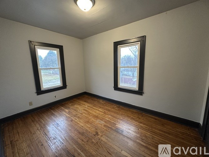 A room with wooden floors and two windows.