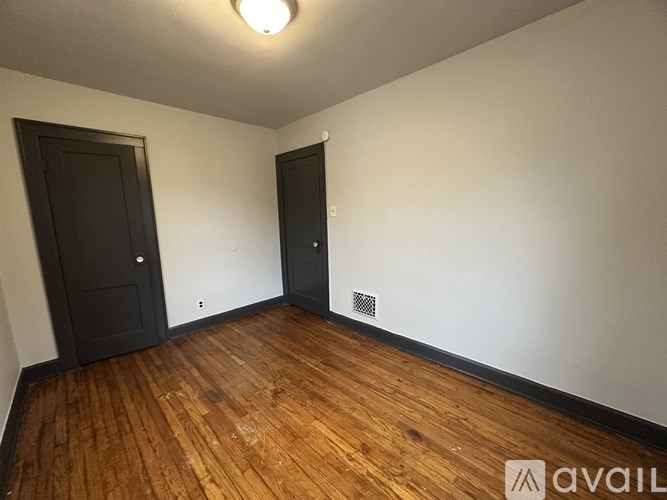 A room with wooden floors and two doors.