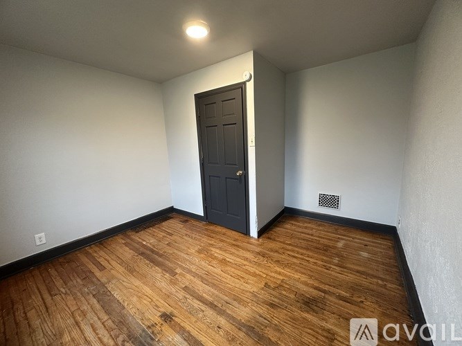 A room with a wooden floor and a black door.