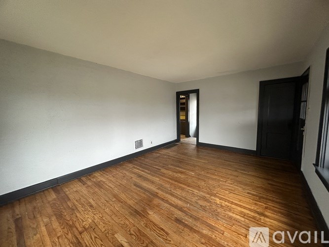 A room with wooden flooring and a door in the background.
