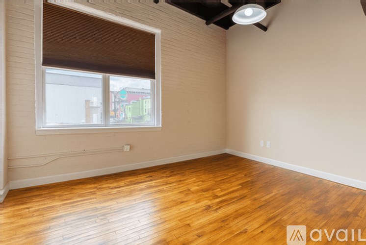 A room with wooden flooring and a window with blinds.