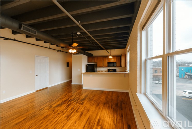 A room with wooden floors and a large window overlooking a street.