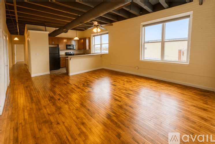 A spacious room with wooden floors and a large window.