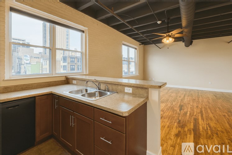 A kitchen with wooden cabinets and a black trash can.