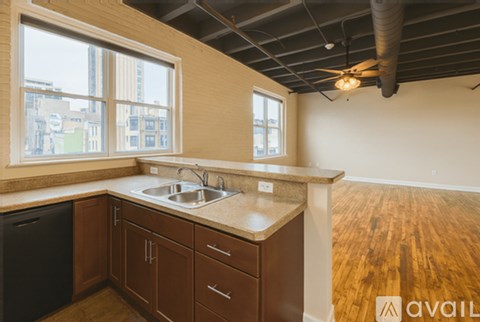 A kitchen with wooden cabinets and a black trash can.