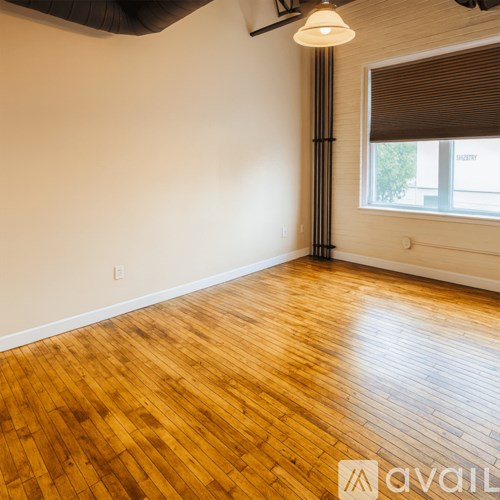 A room with wooden flooring and a window with blinds.