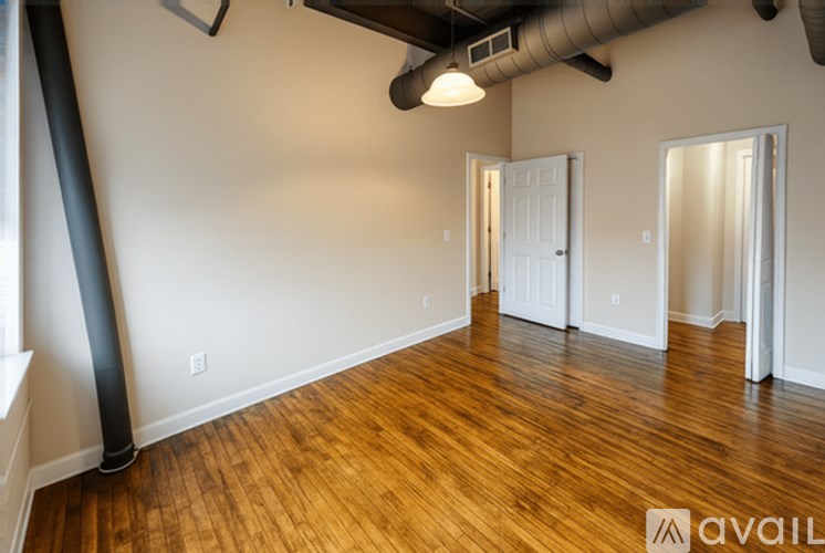 A room with wooden floors and white walls, with a door on the right side.
