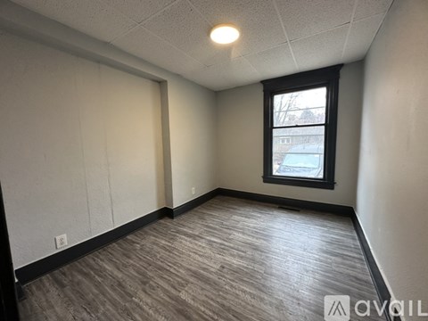 A room with a window and a wooden floor.