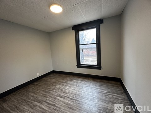A room with a window and a wooden floor.