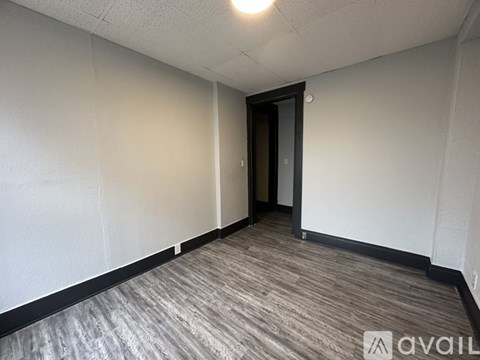 A hallway with a door at the end and a carpet on the floor.