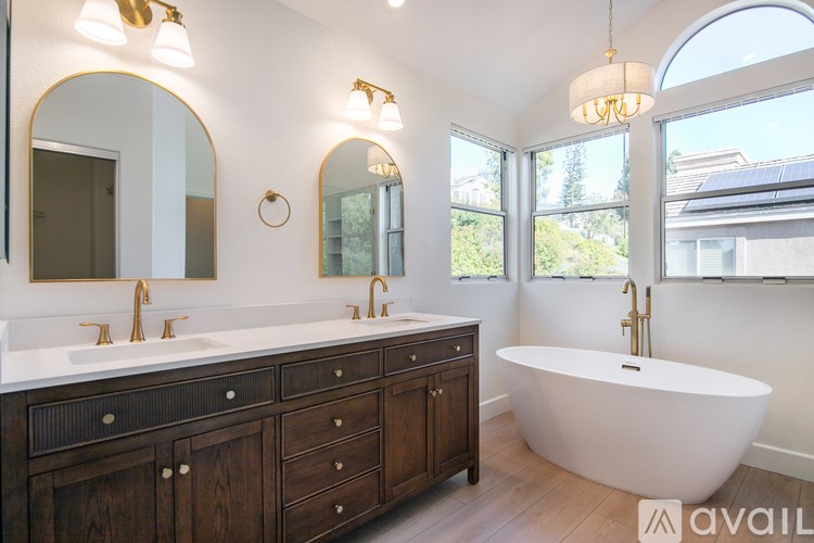 A bathroom with a tub, sink, and mirror.