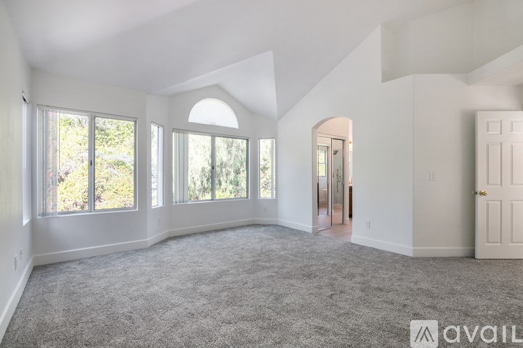 A spacious room with a carpeted floor and a large window.