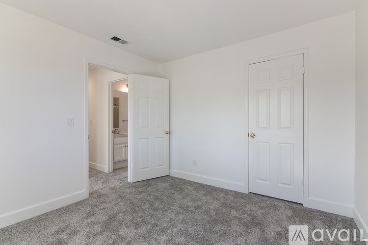 A room with a carpeted floor and two doors.