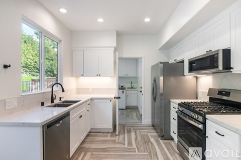 A modern kitchen with white cabinets and a black stove top oven.