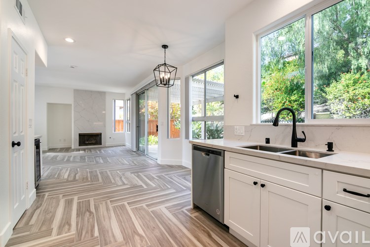 A modern kitchen with a large island and a fireplace in the living room.