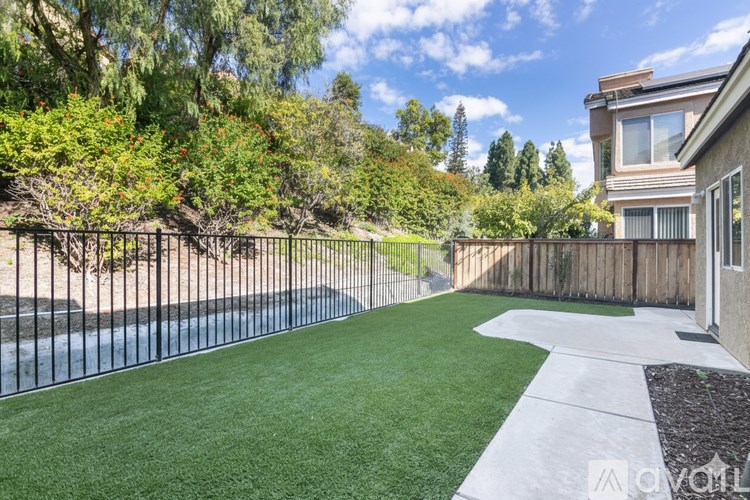A backyard with a black fence and a green lawn.