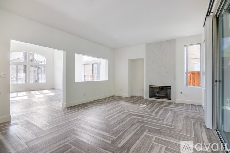 A spacious living room with a fireplace and a herringbone patterned floor.