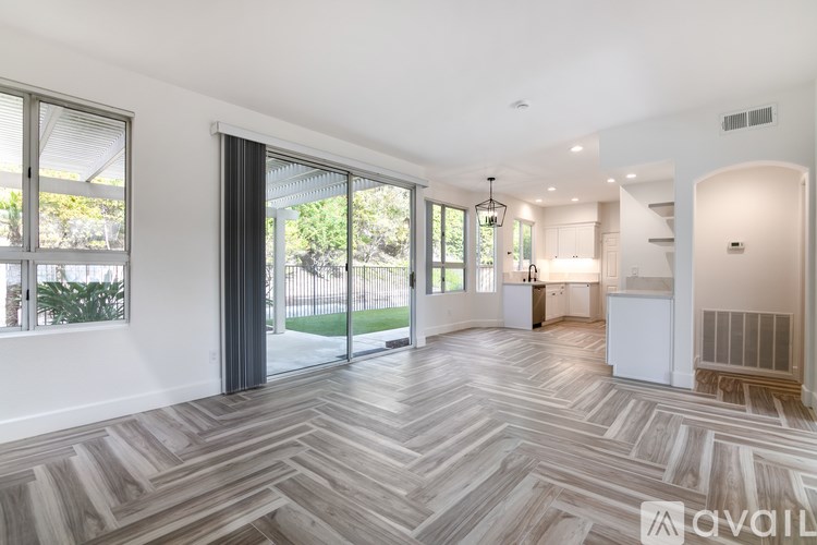 A spacious living room with a herringbone patterned floor and sliding glass doors.
