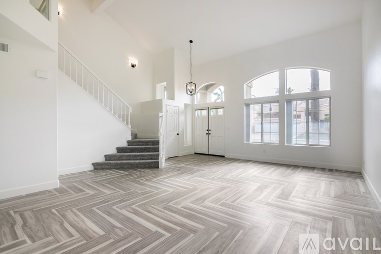 A spacious room with a staircase and a large window.