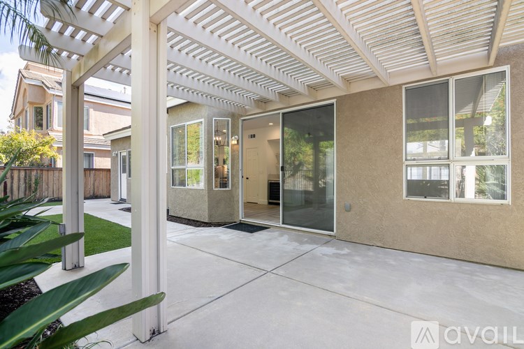 A patio area with a pergola and glass doors.