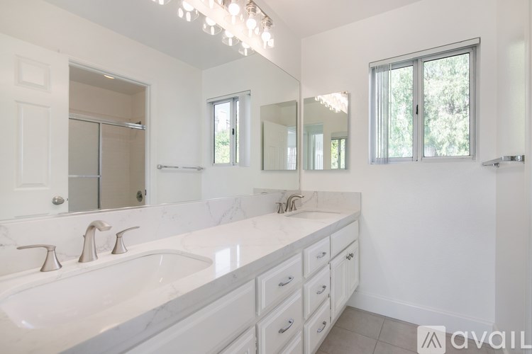 A bathroom with a large mirror, a sink, and a window.