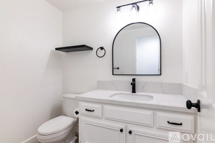 A white bathroom with a toilet, sink, and mirror.