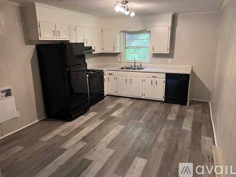 A kitchen with black appliances and white cabinets.