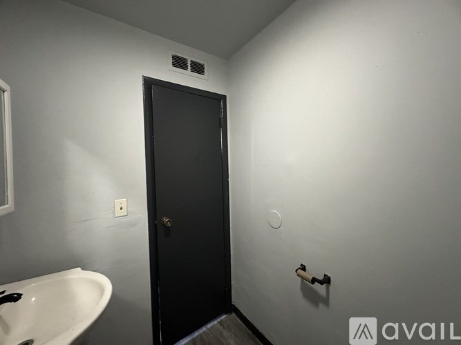 A bathroom with a sink, mirror, and black door.