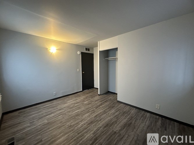 A room with a wooden floor and a light on the wall.