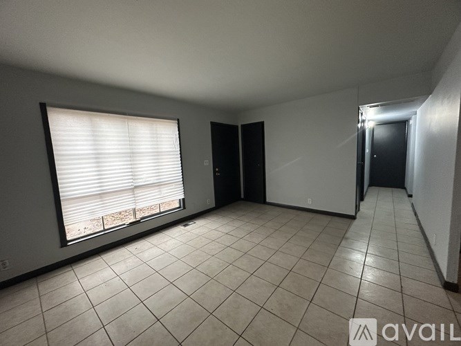 A room with tiled flooring and a window with blinds.