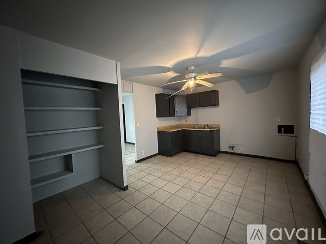 A room with a ceiling fan and a cabinetry unit.