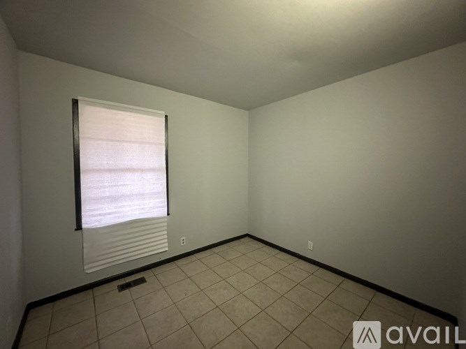A room with a window covered by blinds and tiled flooring.
