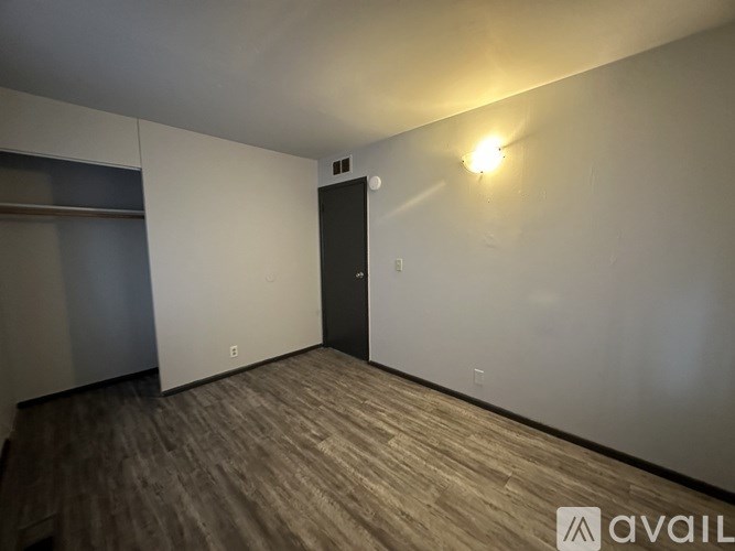 A room with a wooden floor and a black door.