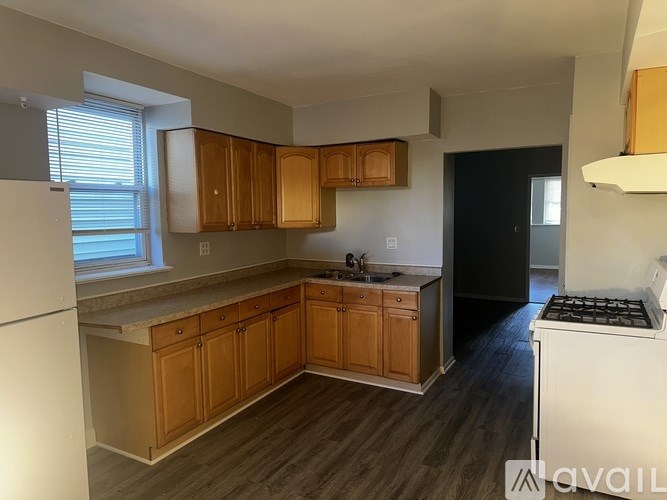 A kitchen with wooden cabinets and a black refrigerator.