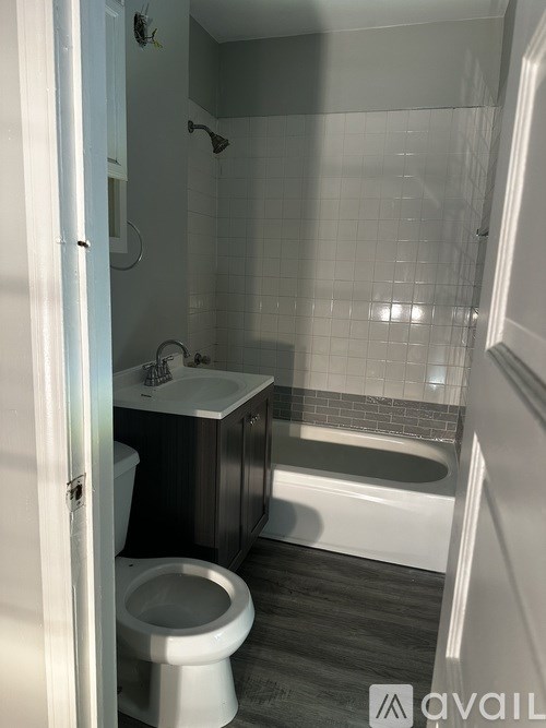 A white toilet is in a bathroom with a white tub and a white shower.