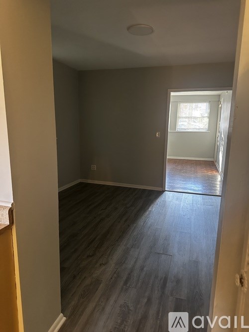 A room with wooden flooring and a door leading to another room.