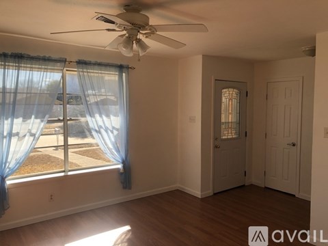 A room with a ceiling fan and a window with curtains.