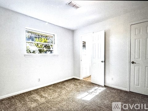 A room with a window, two doors, and a carpeted floor.