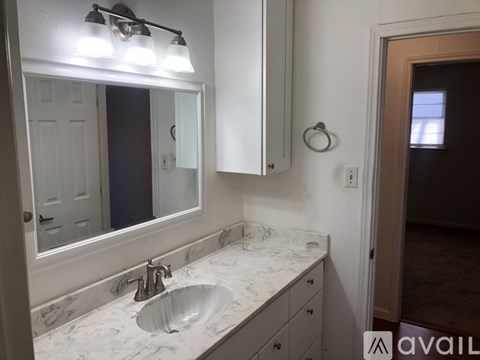 A bathroom with a marble countertop and a large mirror above the sink.