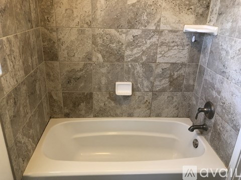 A bathroom with a tiled wall and a white bathtub.