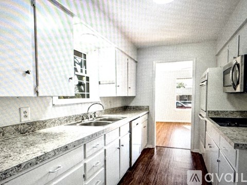 A kitchen with white cabinets and a wooden floor.