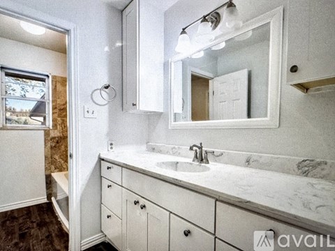 A bathroom with a sink, mirror, and cabinets.
