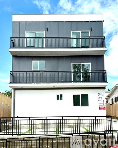 A modern two-story building with balconies and a black railing.
