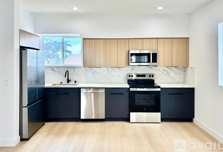 A modern kitchen with dark blue cabinets and stainless steel appliances.