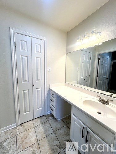 A gravel driveway leads to a house with a grassy field on either side.