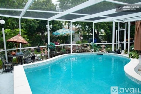 A pool with a glass enclosure and a table and chairs outside.