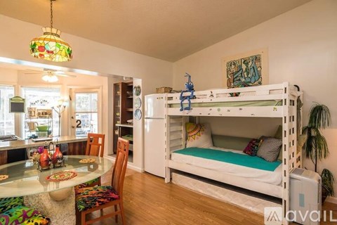 A room with a bunk bed and a dining table.