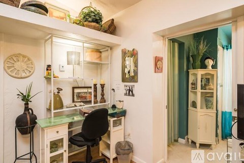 A room with a desk, chair, and shelves filled with various items.